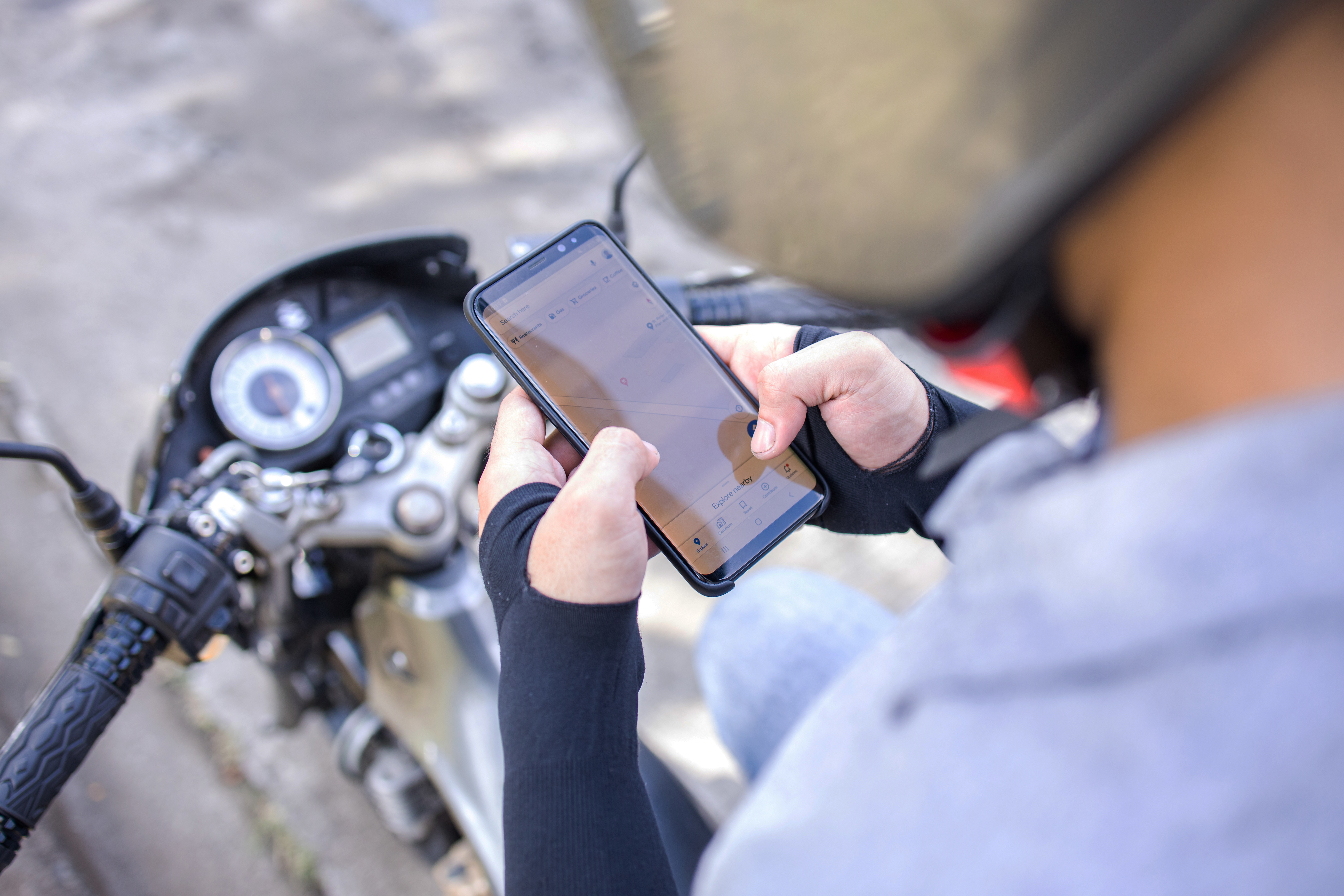 Delivery Man Using Cellphone while Sitting on his Motorcycle 